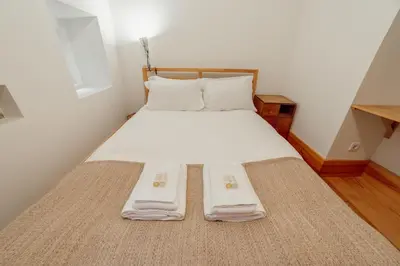 a bed with white sheets and pillows in a room at Historical Duplex by Hosty in Porto
