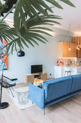 a living room with a blue couch and a palm tree at Batalha Charming Loft in Porto