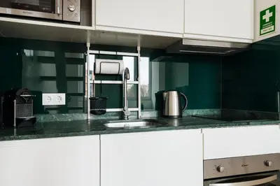 a kitchen with white cabinets and a sink at Mezzanine Studio in the City Center in Porto