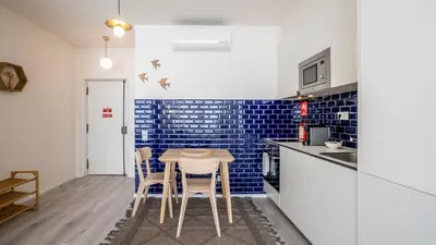 a kitchen with a table and chairs and blue tiles at TrindadeFlat w AC by LovelyStay in Porto