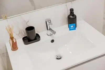 a white bathroom sink with a bottle and a soap dispenser at 252 Heroísmo Duplex Flat in Porto