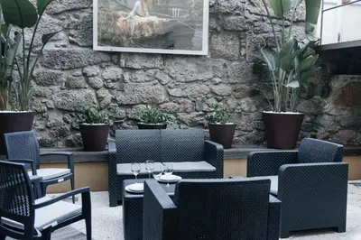 a patio with chairs and tables and a stone wall at Ark of Aqua Flat in Porto