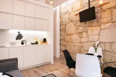 a kitchen with white cabinets and a stone wall at St Ildefonso 02 in Porto