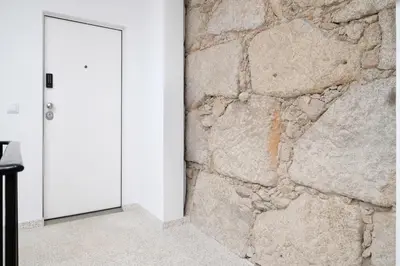 a room with a stone wall and a white door at St Ildefonso 02 in Porto