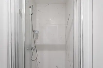 a white bathroom with a shower with a glass door at GuestReady - Homely stay in Porto in Porto