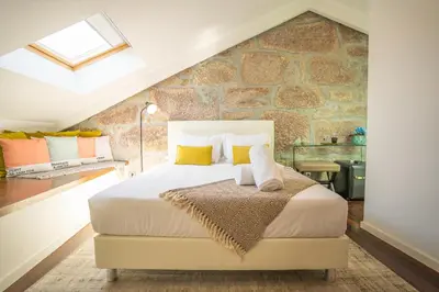 a bedroom with a king sized bed with a stone wall at CHARM by YoursPorto in Vila Nova de Gaia