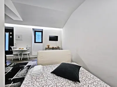 a white bedroom with a bed and a table at Ninho Studio in Vila Nova de Gaia