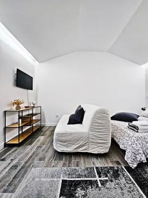 a white bedroom with a bed and a tv at Ninho Studio in Vila Nova de Gaia