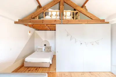 a attic bedroom with a bed and a chandelier at VIVA Boho Chic in Porto