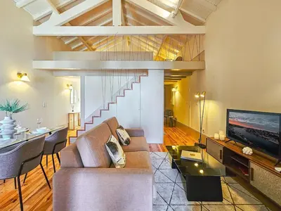 a living room with a couch and a television and a staircase at Wood Haven Luxury Duplex Downtown Porto with AC in Porto
