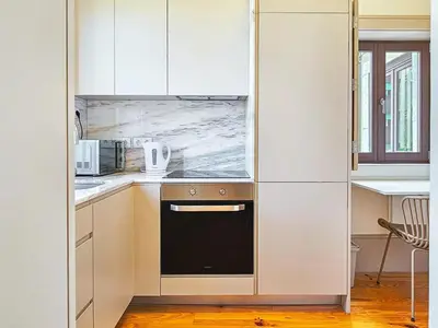 a kitchen with white cabinets and a black oven at Wood Haven Luxury Duplex Downtown Porto with AC in Porto