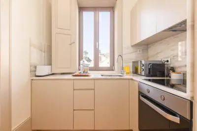 a kitchen with white cabinets and a sink and a window at Wood Haven Luxury Duplex Downtown Porto with AC in Porto