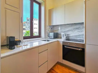 a kitchen with white cabinets and a sink and a window at Wood Haven Luxury Duplex Downtown Porto with AC in Porto