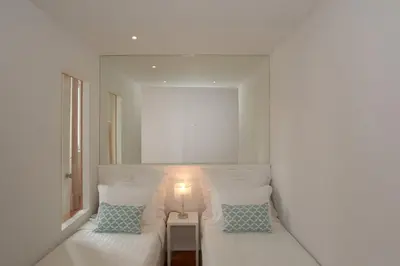 a white bedroom with two beds and a lamp at Bolhão Nobre Apartments in Porto