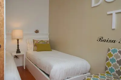 a small bedroom with a bed and a chair at Bolhão Nobre Apartments in Porto