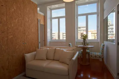 a living room with a couch and two windows at Bolhão Nobre Apartments in Porto