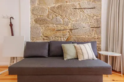a couch in a living room with a stone wall at Cozee Bonjardim in Porto