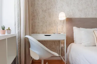a bedroom with a white chair next to a bed at Cozee Bonjardim in Porto