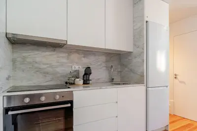 a kitchen with white cabinets and a refrigerator at Topazio Apartment by Porto Stories in Porto