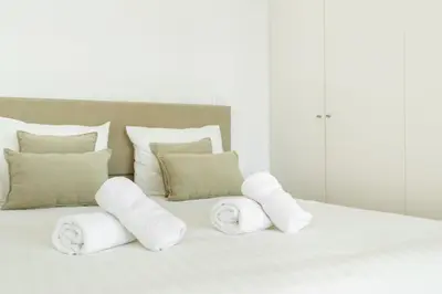 a white bed with white pillows and towels on it at Home M apartments in Porto