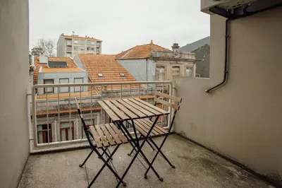 a wooden table and chair sitting on a balcony at Cedofeita Flat by Hosty in Porto