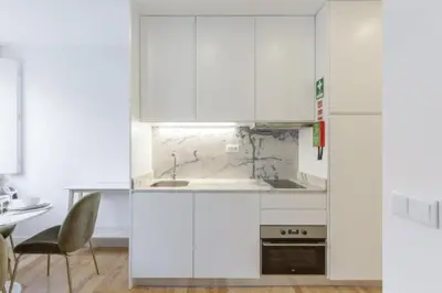 a kitchen with white cabinets and a table and a chair at OPorto Cosy and Modern Loft in Porto