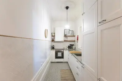 a white kitchen with white cabinets and a sink at Alegria Rubi - Urban Oasis with Garden in Porto