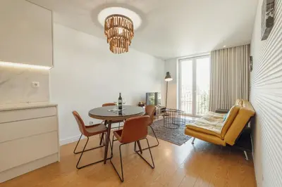 a kitchen with white cabinets and a table with chairs at Downtown Bright Apartment With Balcony by Vacationy in Porto