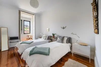 two beds in a room with white walls and wood floors at Hidden Gem near city center- garden, outdoor kitchen, sauna in Porto