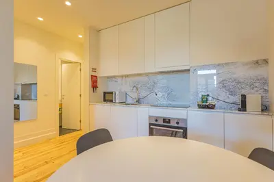 a white kitchen with a table and chairs at Firmeza Gardens in Porto