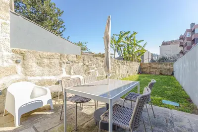 a patio with a glass table and chairs at Firmeza Gardens in Porto