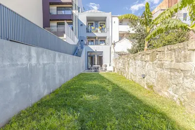 a stone wall next to a building with a yard at Firmeza Gardens in Porto