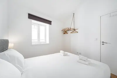 a white bedroom with a white bed and a window at GuestReady - Oporto Old Town House 3 in Porto