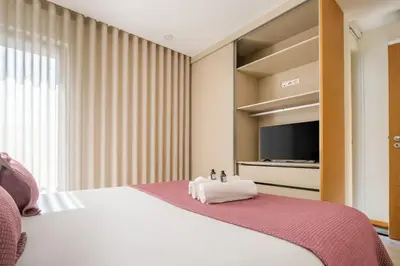 a bedroom with a white bed and a television at Wonderfull apartment Campanhã Train station with parking in Porto
