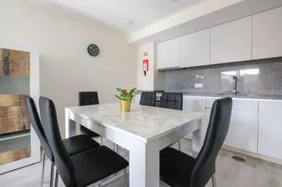 a white kitchen with a white table and black chairs at Wonderfull apartment Campanhã Train station with parking in Porto