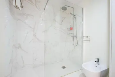a white bathroom with a shower and a sink at Wonderfull apartment Campanhã Train station with parking in Porto