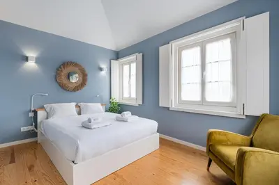 a blue bedroom with a white bed and a chair at GuestReady - Souto Downtown Studios in Porto
