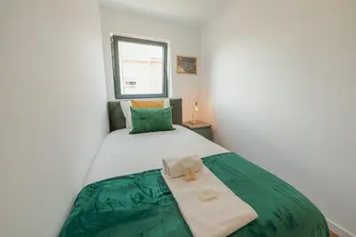 a bedroom with a bed with green sheets and a window at Lapa Stylish Apartments by Vacationy in Porto