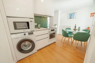a kitchen with a washing machine and a table with chairs at Lapa Stylish Apartments by Vacationy in Porto