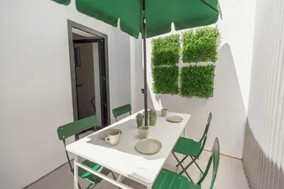 a white table with green chairs and an umbrella at Lapa Stylish Apartments by Vacationy in Porto