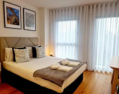a bedroom with a large bed with white curtains at Porto Trindade Balcony in Porto