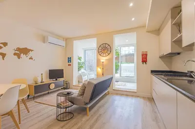 a kitchen and a living room with a table at Marilia's Garden Apartment in Porto