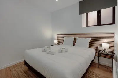 a white bedroom with a large white bed with two lamps at House River View by Best2Stay in Vila Nova de Gaia