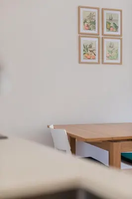 a wooden table with a white chair and pictures on the wall at Downtown Refuge Camões in Porto
