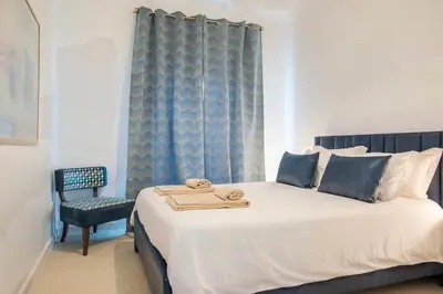 a bedroom with a large bed and a chair at Family Porto in Porto