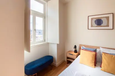 a bedroom with a bed and a blue chair at Miragaia Studio w Patio by LovelyStay in Porto