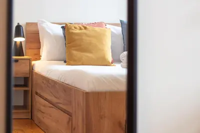 a bed with a wooden headboard with a yellow pillow at Miragaia Studio w Patio by LovelyStay in Porto
