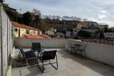 a patio with chairs and tables on a balcony at Miragaia Studio w Patio by LovelyStay in Porto