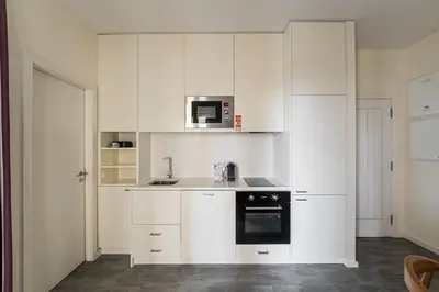 a white kitchen with white cabinets and a microwave at GuestReady - One perfect home near the city centre in Porto