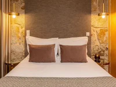 a bed with white sheets and pillows in a room at City Apartment with River Views in Vila Nova de Gaia